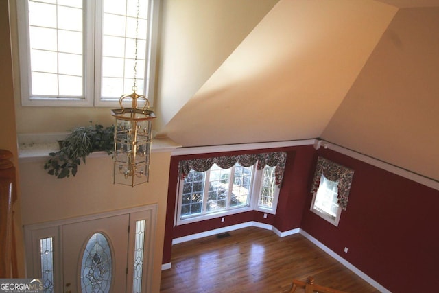 foyer with lofted ceiling, baseboards, visible vents, and dark wood finished floors