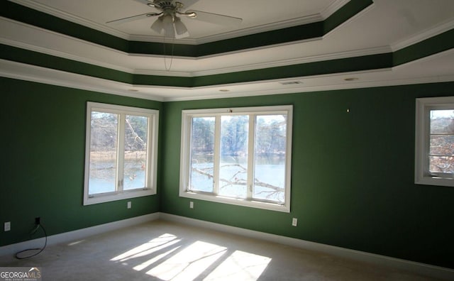 empty room featuring baseboards, ornamental molding, a raised ceiling, and light colored carpet