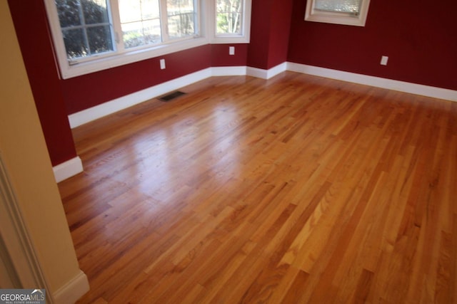 unfurnished room featuring wood finished floors, visible vents, and baseboards