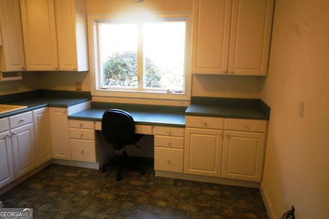 unfurnished office featuring baseboards, stone finish floor, and built in study area