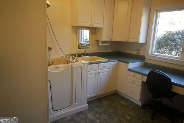 kitchen with plenty of natural light, white cabinets, and a sink