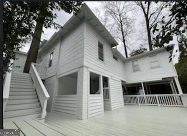 back of property featuring stairway and a deck