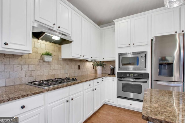 kitchen with white cabinetry, decorative backsplash, stainless steel appliances, and dark stone counters