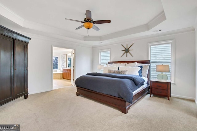 carpeted bedroom featuring ceiling fan, ensuite bath, ornamental molding, and a raised ceiling