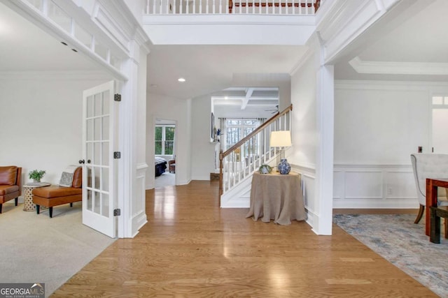 foyer featuring a high ceiling, ornamental molding, and light hardwood / wood-style flooring