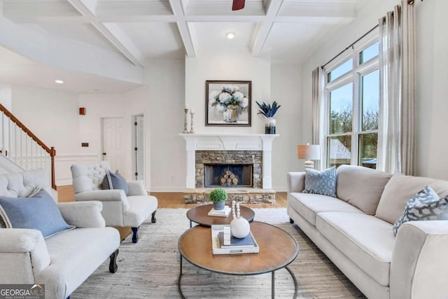 living room with beamed ceiling, wood-type flooring, coffered ceiling, and a stone fireplace