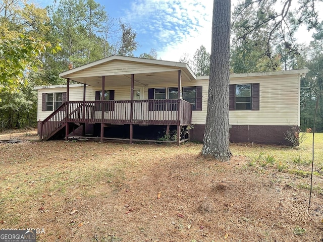 manufactured / mobile home featuring a wooden deck and a front yard