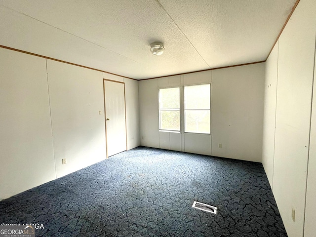 carpeted empty room with a textured ceiling