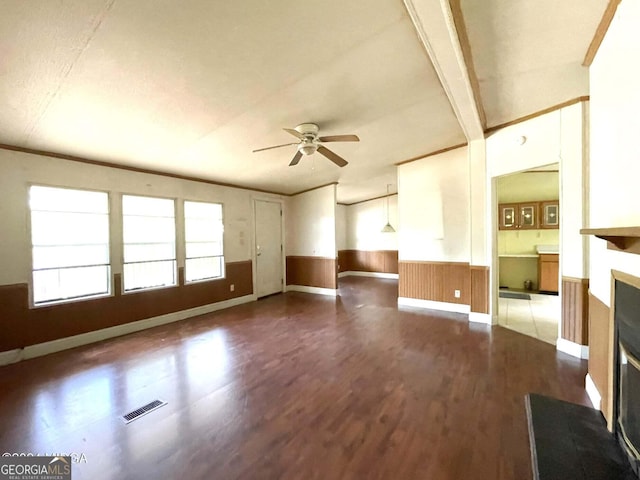 unfurnished living room with hardwood / wood-style flooring, ceiling fan, crown molding, and wood walls