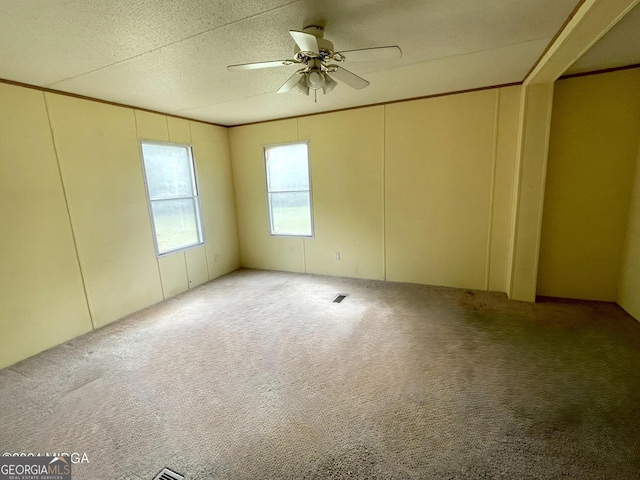 unfurnished room featuring crown molding, carpet, a textured ceiling, and ceiling fan