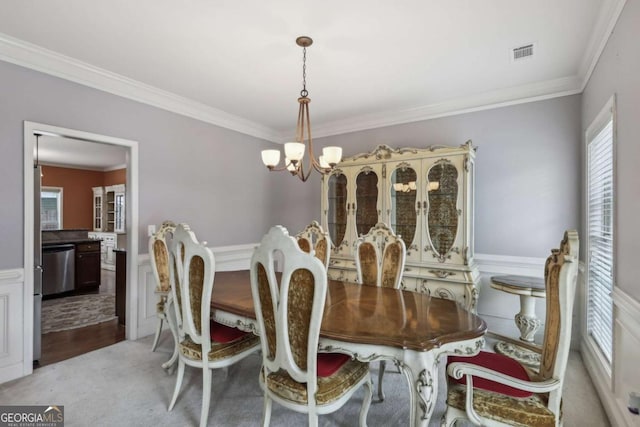 dining space with ornamental molding, light colored carpet, and an inviting chandelier