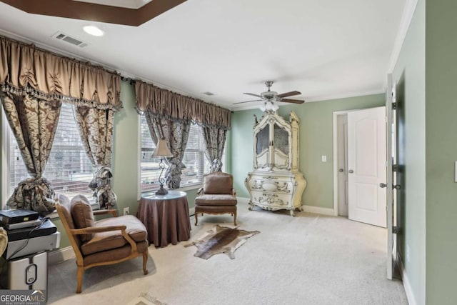 living area with ornamental molding, light colored carpet, and ceiling fan