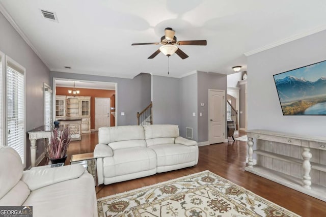 living room with ceiling fan with notable chandelier, ornamental molding, and dark hardwood / wood-style floors