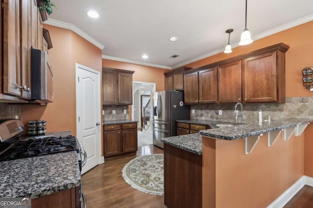 kitchen with sink, dark stone countertops, hanging light fixtures, stainless steel appliances, and kitchen peninsula