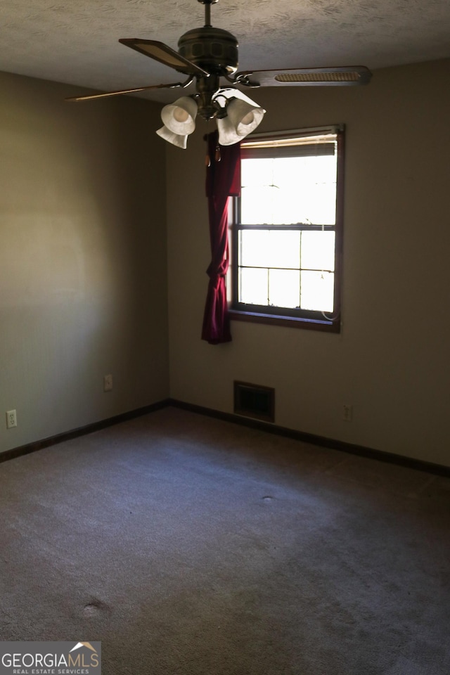 carpeted spare room featuring baseboards, ceiling fan, a textured ceiling, and visible vents