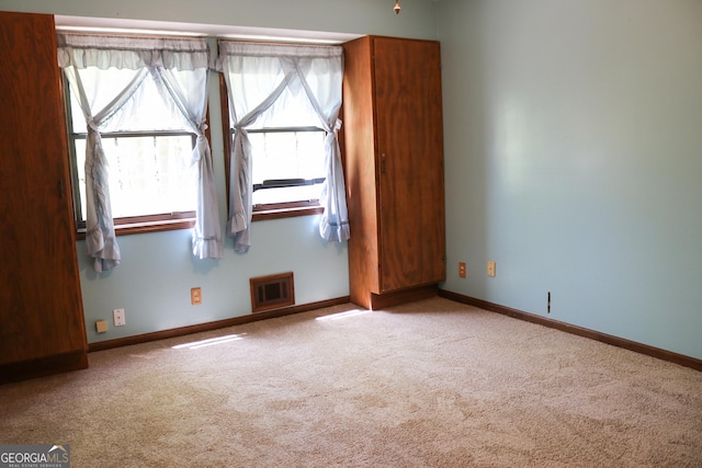 carpeted empty room featuring baseboards and visible vents