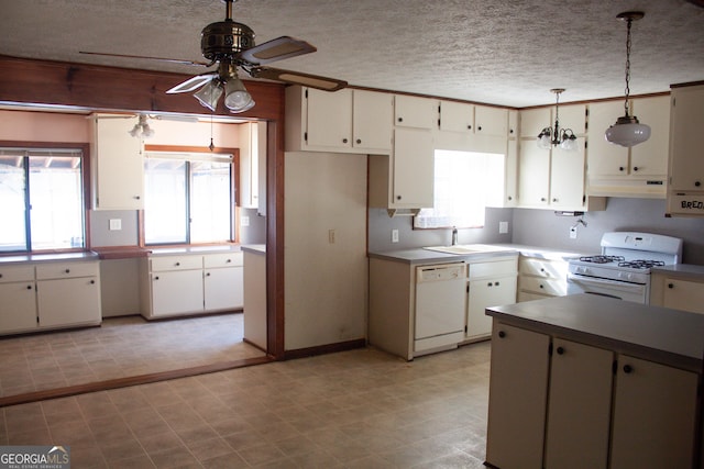 kitchen featuring sink, white appliances, hanging light fixtures, a textured ceiling, and white cabinets