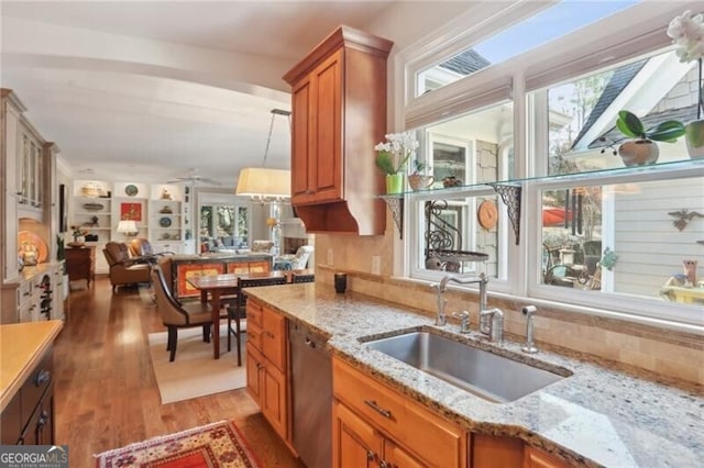 kitchen with light stone counters, sink, light hardwood / wood-style flooring, and dishwasher