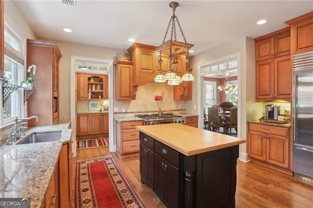 kitchen with sink, light hardwood / wood-style flooring, appliances with stainless steel finishes, a kitchen island, and pendant lighting