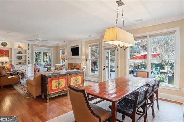 dining area with hardwood / wood-style flooring, ornamental molding, plenty of natural light, and ceiling fan with notable chandelier