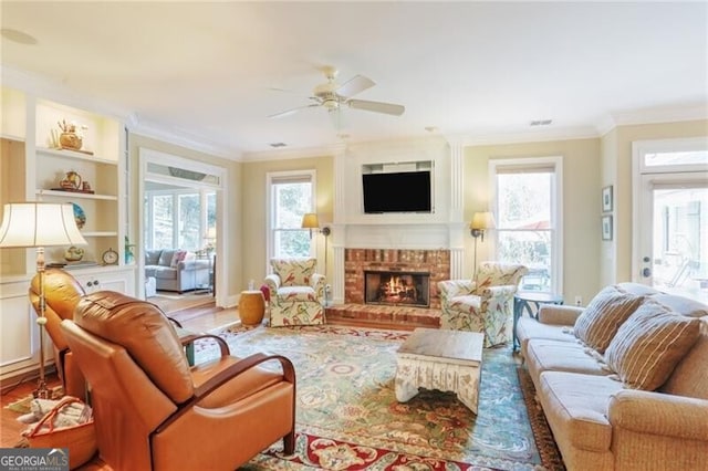 living room featuring ceiling fan, ornamental molding, wood-type flooring, and a brick fireplace