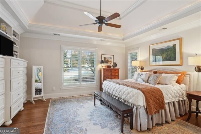 bedroom featuring ornamental molding, dark wood-type flooring, ceiling fan, and a tray ceiling