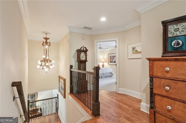 hall with ornamental molding, an inviting chandelier, and light hardwood / wood-style floors