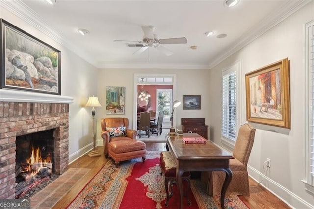 living area featuring crown molding, ceiling fan, wood-type flooring, and a brick fireplace