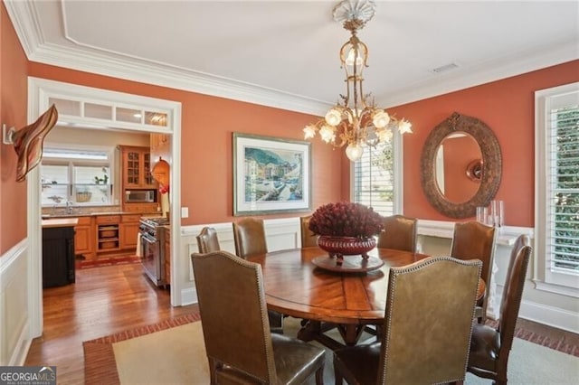 dining room featuring crown molding, sink, hardwood / wood-style flooring, and a chandelier