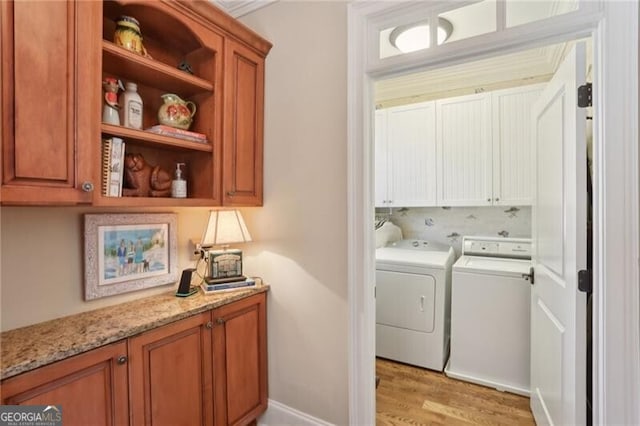 washroom with light hardwood / wood-style flooring, washer and clothes dryer, and cabinets