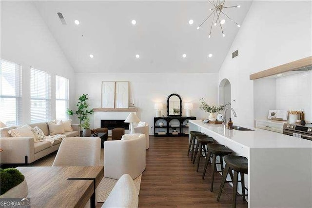 living room featuring dark hardwood / wood-style flooring, high vaulted ceiling, sink, and a chandelier