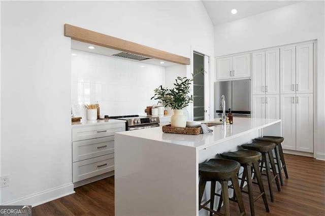 kitchen featuring dark hardwood / wood-style floors, sink, a breakfast bar area, a kitchen island with sink, and stainless steel appliances