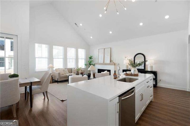 kitchen with white cabinetry, high vaulted ceiling, a center island with sink, dark hardwood / wood-style flooring, and stainless steel dishwasher