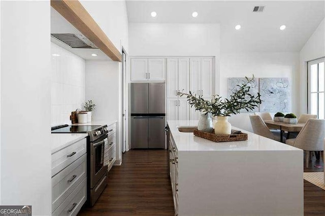 kitchen featuring dark hardwood / wood-style flooring, a center island, white cabinets, and appliances with stainless steel finishes