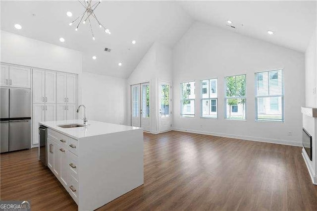 kitchen with appliances with stainless steel finishes, an island with sink, sink, white cabinets, and dark hardwood / wood-style flooring