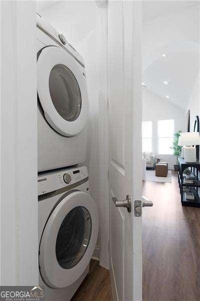 laundry area featuring stacked washer and dryer and dark hardwood / wood-style floors