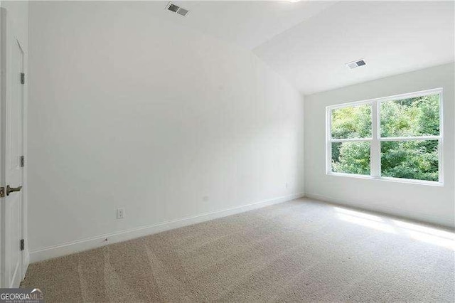 carpeted empty room with lofted ceiling