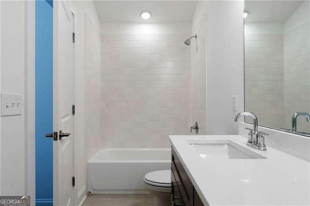 full bathroom with vanity, tiled shower / bath, and toilet