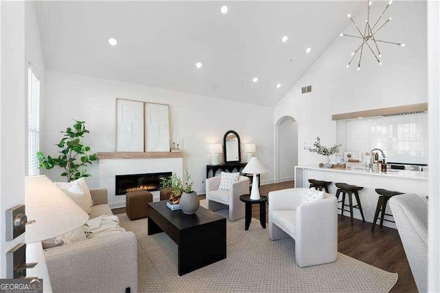 living room featuring high vaulted ceiling, wood-type flooring, a chandelier, and sink