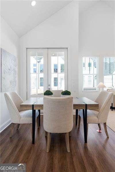 dining space with wood-type flooring, high vaulted ceiling, and french doors