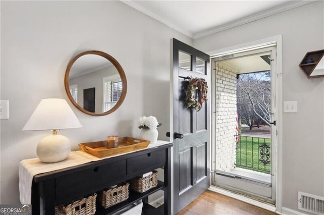 doorway to outside with crown molding, a healthy amount of sunlight, and hardwood / wood-style flooring