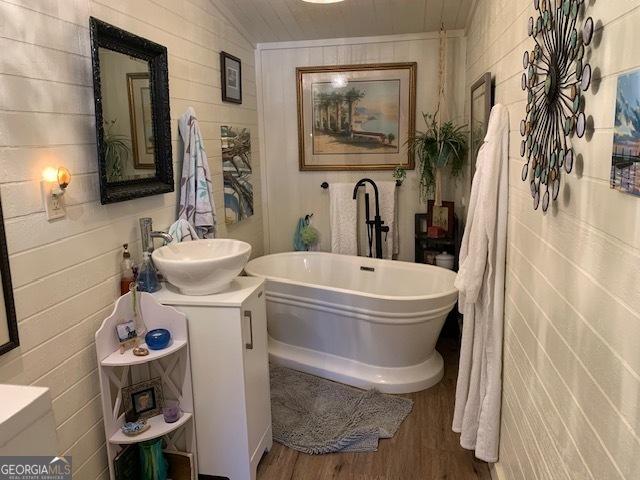 bathroom with a tub to relax in, hardwood / wood-style floors, and vanity