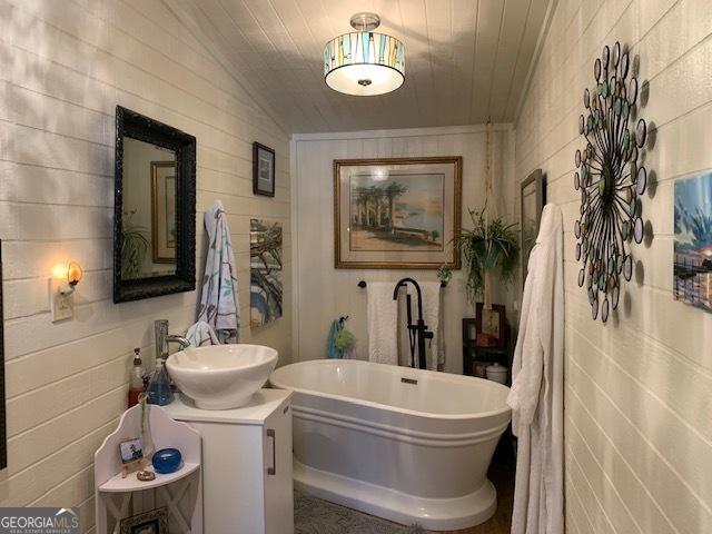 bathroom featuring vanity, lofted ceiling, and a bath