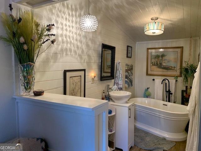 bathroom featuring vanity, vaulted ceiling, and a tub