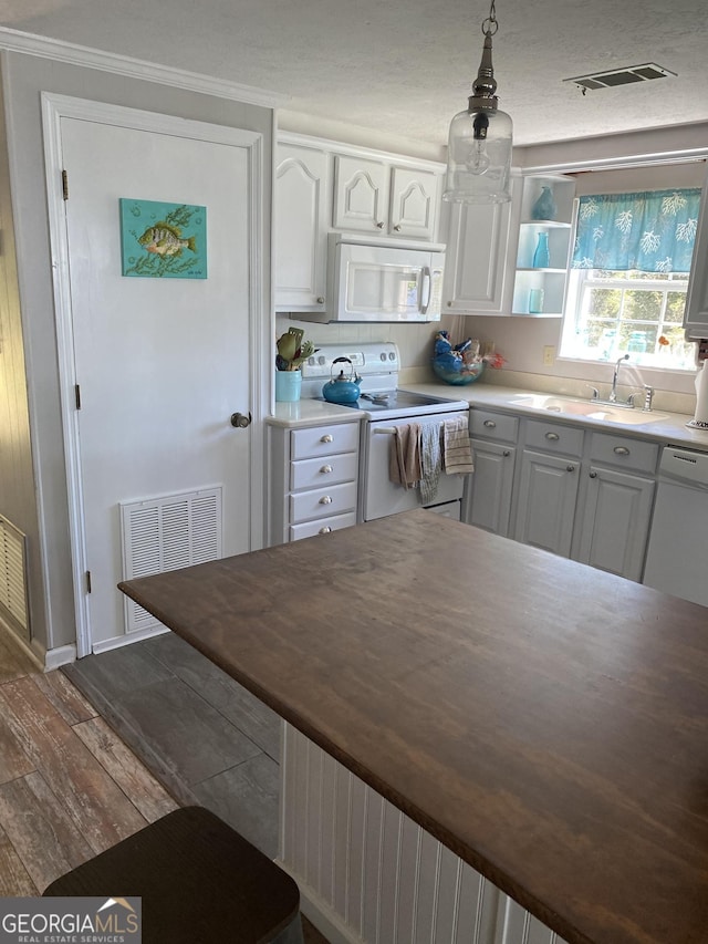 kitchen with a sink, visible vents, white appliances, and white cabinetry