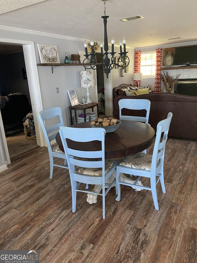 dining space featuring ornamental molding, wood finished floors, visible vents, and a chandelier
