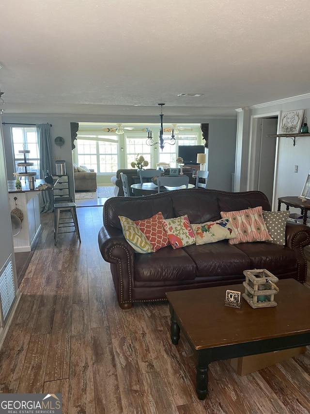 living area featuring visible vents, a healthy amount of sunlight, dark wood-style flooring, and ornamental molding