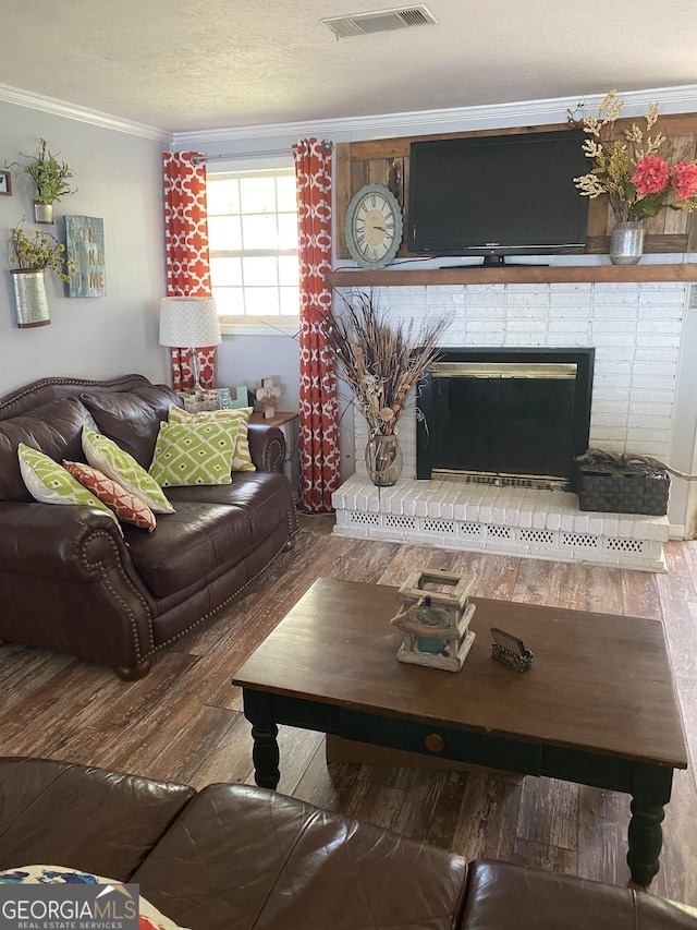 living area featuring a fireplace, wood finished floors, visible vents, and ornamental molding