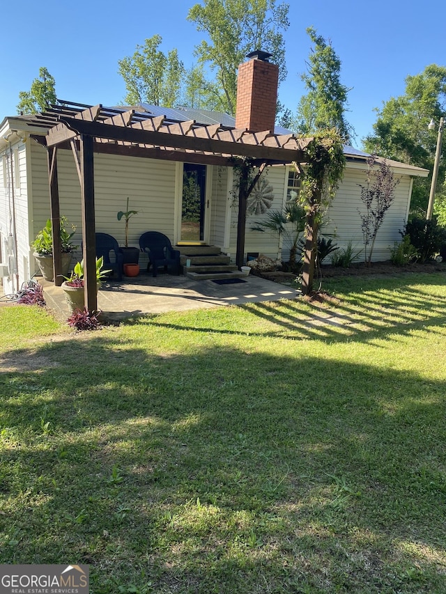 rear view of property featuring a yard, a patio area, a chimney, and a pergola