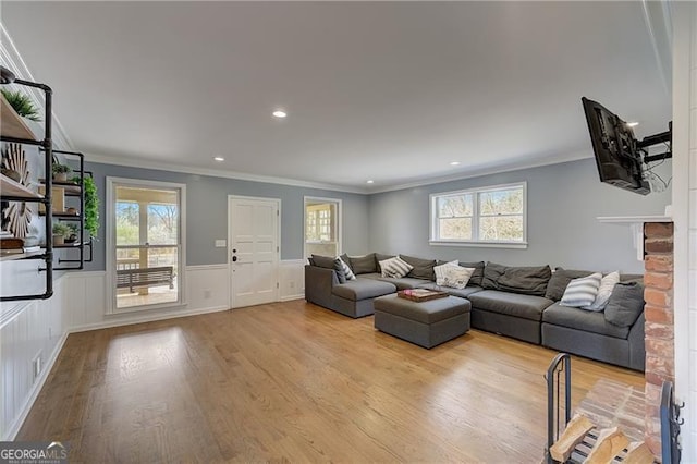 living room with a brick fireplace, crown molding, and light hardwood / wood-style floors